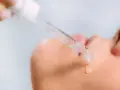 Kropla serum z kwasami AHA spada na skórę.