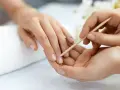 Delikatne dłonie poddawane są zabiegowi manicure biologicznego. Drewniany patyczek delikatnie odsuwa skórki, przygotowując paznokcie do dalszych pielęgnacji.