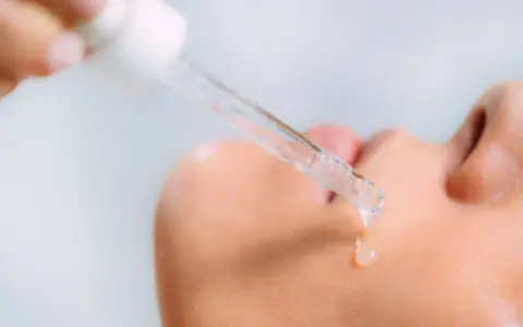 Kropla serum z kwasami AHA spada na skórę.
